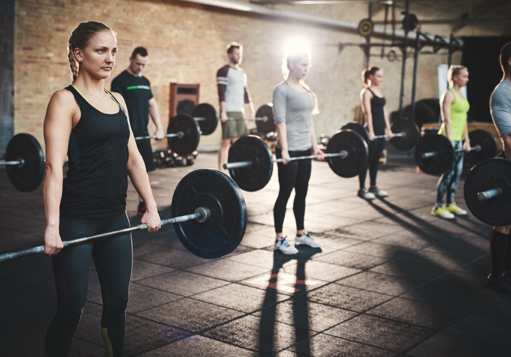 students in crossfit class holding barbells